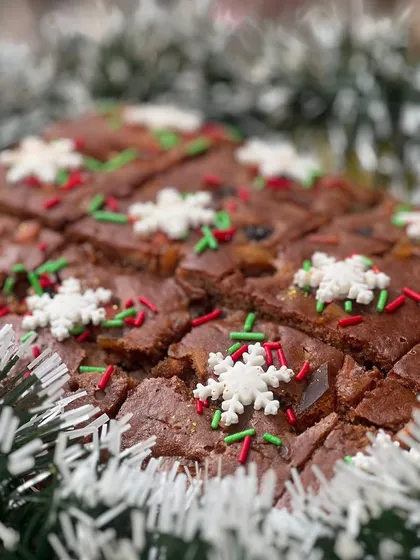 A rich and moist Christmas fruitcake, decorated with festive sprinkles and edible snowflakes.