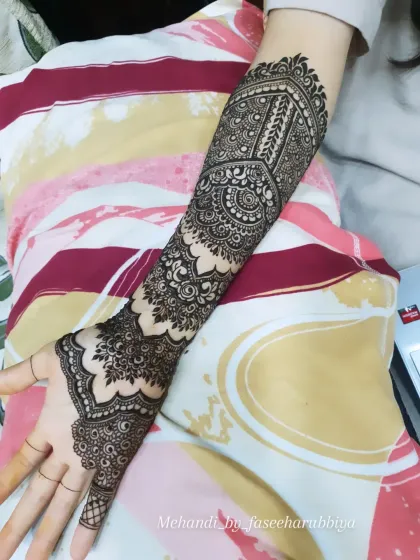 A single-arm view of Shaziya's engagement henna, showing the detailed cuff and finger work.