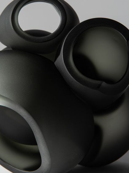 A detailed shot of the matte, dark grey finish of the Bocci 100 series pendants, highlighting their smooth, sculptural quality.