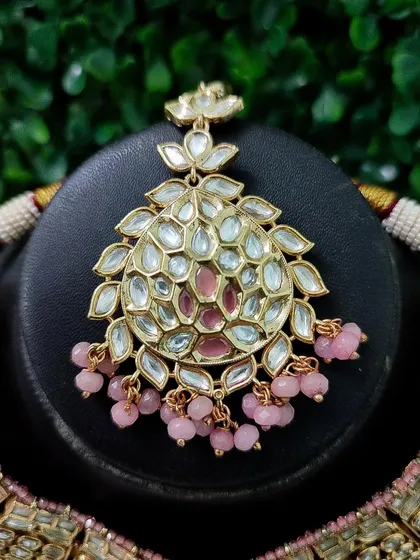 A close-up of the maang tikka from the pink set, showing its intricate design.