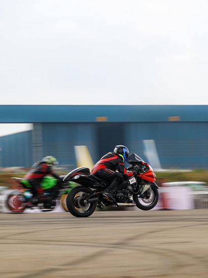 Two superbikes launch off the line in a cloud of smoke, front wheels lifting off the tarmac. This is the explosive start to a quarter-mile battle.