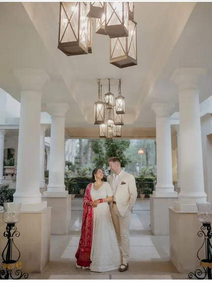 An elegant portrait of a cross cultural couple, Isha and Kyle, under a beautifully lit colonnade. This image represents our passion for telling stories of love that bridge distances, captured with a timeless, classic feel.