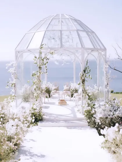 For this destination wedding in Bali, I envisioned a mandap that felt both ethereal and one with nature. A modern glasshouse perched on a cliff, overlooking the ocean, created a breathtaking backdrop for a truly romantic garden soiree.