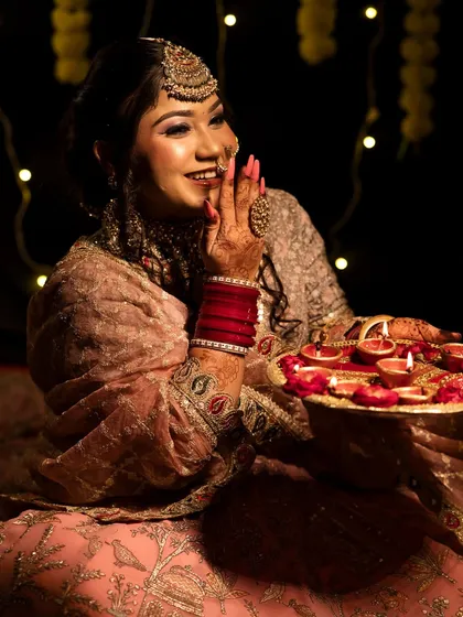 The bride holds a tray of diyas, her smile and radiant makeup lighting up the frame. This is a great example of a themed portfolio shoot.