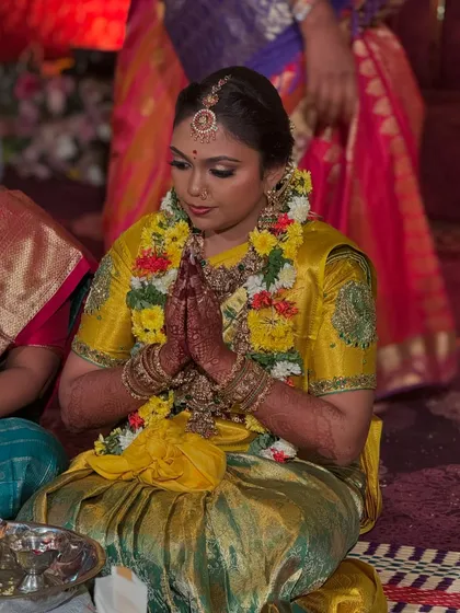 Prithivi in a moment of prayer during her wedding. Her makeup remains flawless, with the focus on her expressive eyes and the overall radiance of her bridal look.