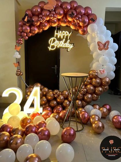 A beautiful rose gold and white balloon ring with butterfly accents and a light-up number '24' for an elegant birthday.