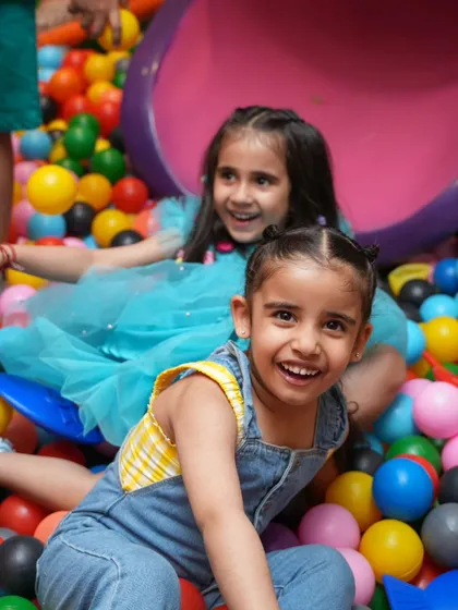 Two friends sharing a huge smile while playing in the ball pit.