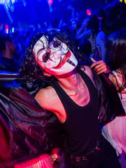 A guest in a V for Vendetta mask at a Halloween party.