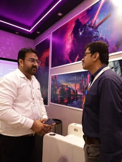 Visitors engage with an exhibitor in a booth featuring dramatic, colorful wall art, showing how creative booth design can attract attention and create a memorable experience.