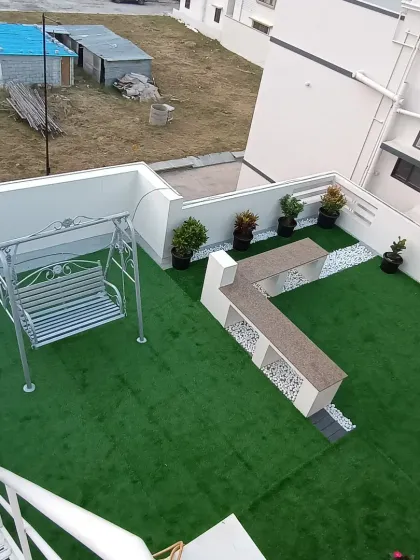 An aerial view of a terrace transformed with artificial grass. I also installed a custom L-shaped bench and a swing, creating a complete outdoor lounge area.