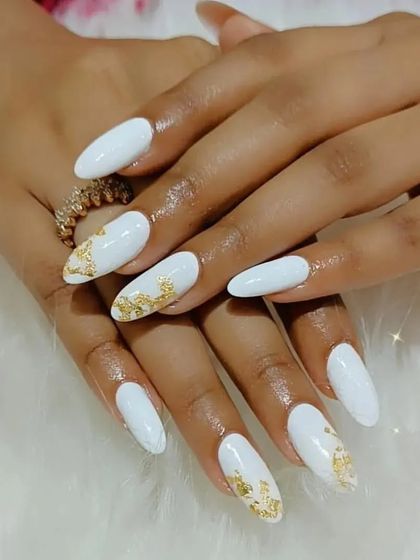 A chic and elegant set of long white almond nails with gold foil accents for a touch of luxury.