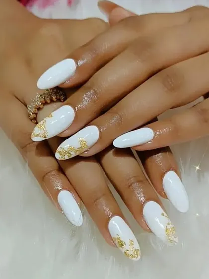 A chic and elegant set of long white almond nails with gold foil accents for a touch of luxury.