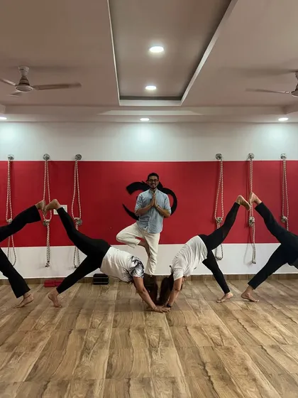 The energy in my studio, Yoga Dhara, is something special. It’s a space of shared effort, laughter, and fearless practice. Here, we support each other in exploring our limits, like in this group variation of a three-legged downward dog.