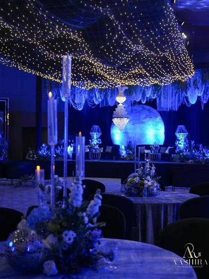 A beautiful shot from a dining table, looking towards the moonlit stage, with a tall candelabra in the foreground adding to the romantic ambiance.