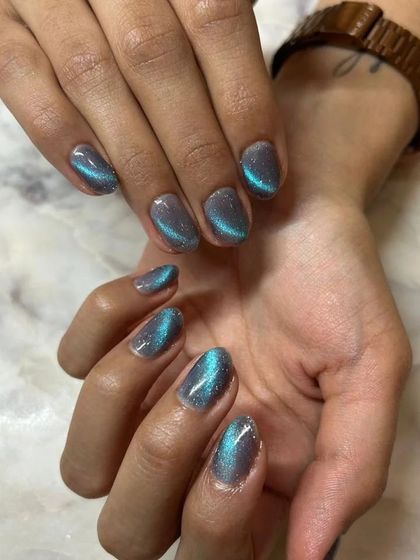 This shot captures the beautiful shimmer of the teal cat-eye polish against the client's skin tone.