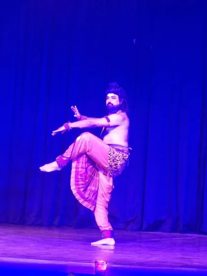 A solo performance under the vibrant blue stage lights. The lighting and stagecraft in our productions are carefully designed to enhance the mood and highlight the intricate movements of the dance.