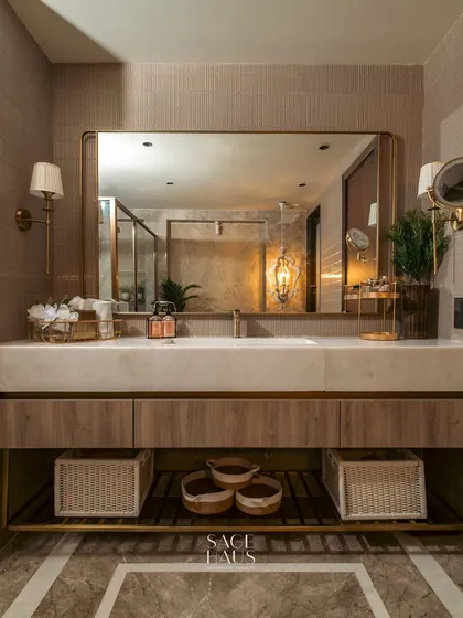 This master bathroom vanity is designed for both luxury and function. The warm wood cabinetry, white onyx countertop, and ample storage are complemented by elegant wall sconces and a large, simple mirror that makes the space feel expansive.
