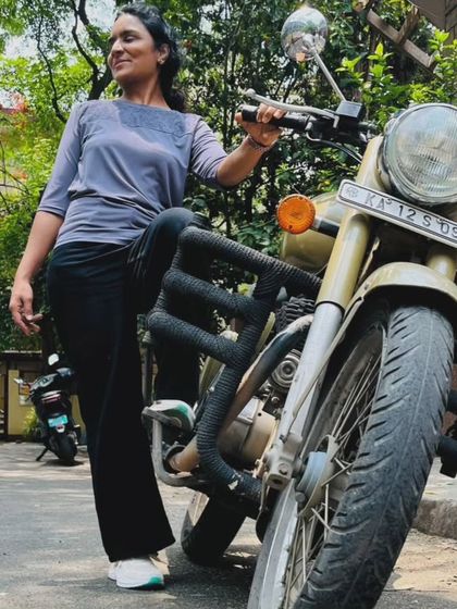 A graduate stands proudly with her Royal Enfield. She is a testament to the fact that any woman can learn to ride.