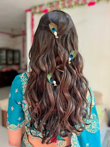 The hairstyle for this look was soft, open curls, adorned with beautiful peacock feather accessories for a unique, traditional touch.