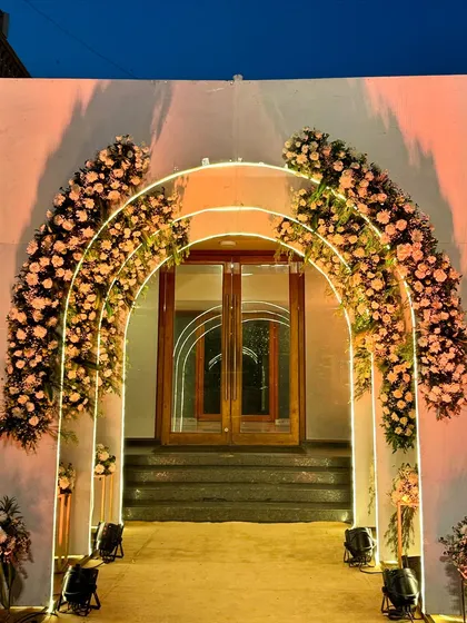 The floral and light arches against the evening sky, creating a magical and inviting entrance to the celebration.