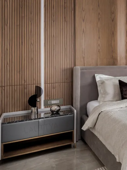 The custom bedside table in the son's room features a grey marble top and a sleek, modern design, set against a wall of vertical wood fluting with integrated lighting.