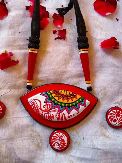I designed this eye-shaped pendant to be a unique canvas, combining colorful mandala art with the flowing white lines of Bengali alpona. This red version is particularly striking and comes with matching circular earrings.