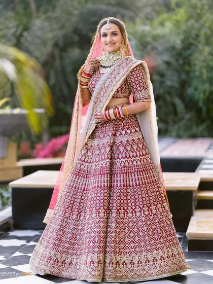 A radiant bride in her classic red lehenga, smiling brightly at her Udaipur palace wedding.