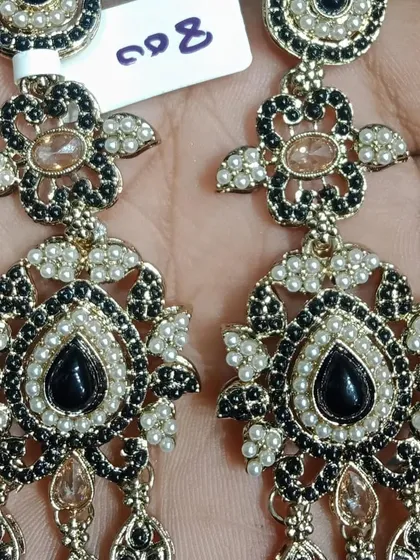 A pair of elegant black and pearl earrings with an antique gold finish. A very classic and versatile color combination.