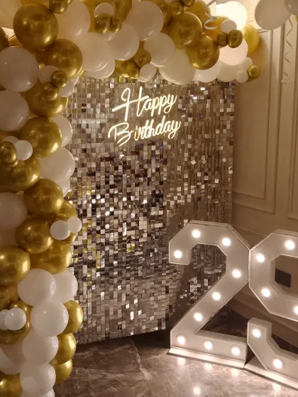 A timeless and elegant choice for any age, this decoration features a shimmering silver sequin wall that serves as a stunning backdrop. I pair it with a balloon arch of white and chrome gold balloons and add large, light-up marquee numbers to highlight the specific age, like the '29' shown here.