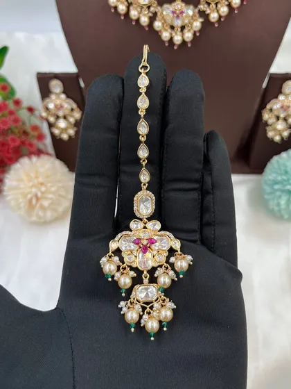 The 'Noor Nazaakat' maang tikka with red and green accents.