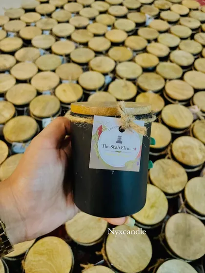 This is an example of our white-labeling service, where we produce products for other brands like The Sixth Element. This black jar candle with a wooden lid and custom tag shows how we can help you launch your own line of scented candles.