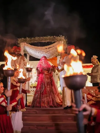 The bride's grand entry, guided by performers with torches. This dramatic entrance creates a powerful and unforgettable visual for your wedding album.