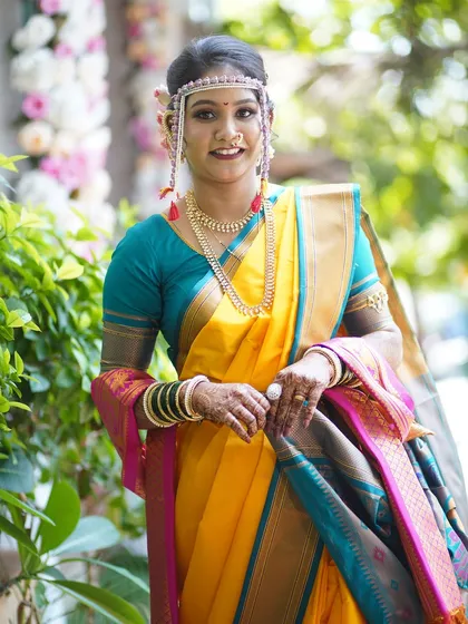 A beautiful portrait of a bride in her yellow and teal Nauvari. The makeup is soft and elegant, perfect for a day wedding, and the look is completed with green bangles and traditional jewellery.