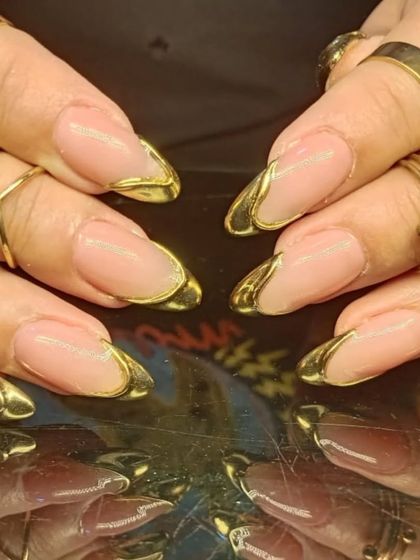 This design showcases a unique, sculpted gold chrome tip that wraps around the nail, creating a futuristic and high-fashion French manicure.