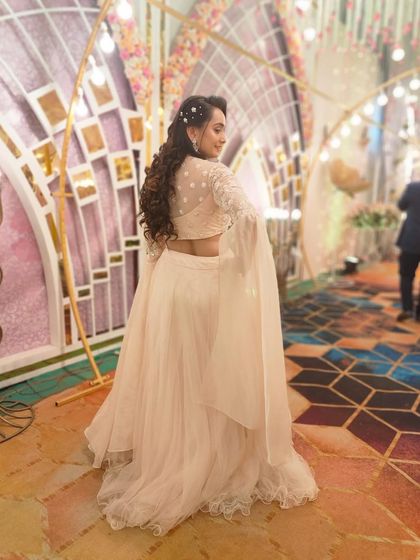A back view of the client in the white bell-sleeved lehenga, showing off the unique design.