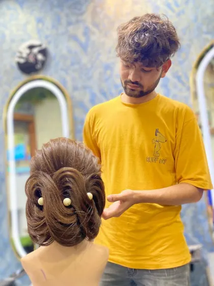 Here, a student assesses his completed updo. This moment of review is an important part of the learning process at my academy.