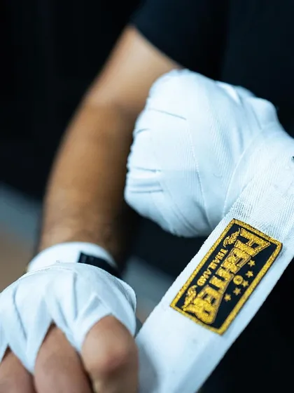 A close-up shot of hands being wrapped with "Fighter" branded wraps. We are all fighters here.