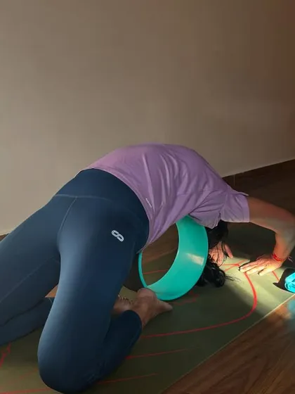 Using a yoga wheel as a prop to help a student safely explore a deep backbend. Props are wonderful tools to make challenging postures more accessible and therapeutic.