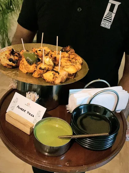 Here is my paneer tikka being served on a platter with fresh mint chutney. I ensure every dish is presented elegantly, whether it's passed around or part of a buffet.