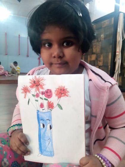 A creative flowerpot drawing by 6-year-old Nataniya. She has given the vase a cartoon face and filled it with bright red flowers using oil pastels.