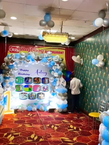 A wide view of the restaurant venue decorated for the elephant-themed first birthday, showing the main backdrop, seating area, and ceiling balloon bunches.