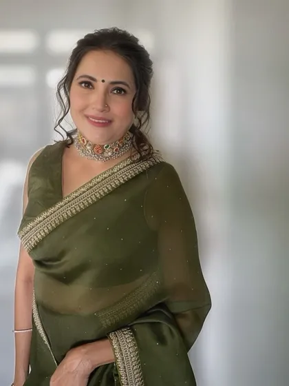 A portrait of the client, looking radiant and confident in her elegant green saree and soft, timeless makeup.