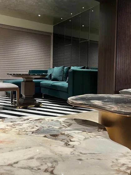 This shot from the Juhu apartment highlights the use of bold color and pattern. A rich teal sofa sits atop a graphic black-and-white striped floor, while a mirrored wall doubles the visual impact.
