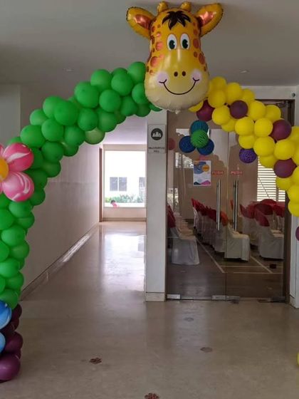 A grand entrance for a jungle-themed party, featuring a balloon arch with a giraffe head and jungle-style signage.