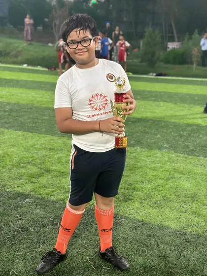 A proud moment for this young footballer, holding the trophy he helped his team win.