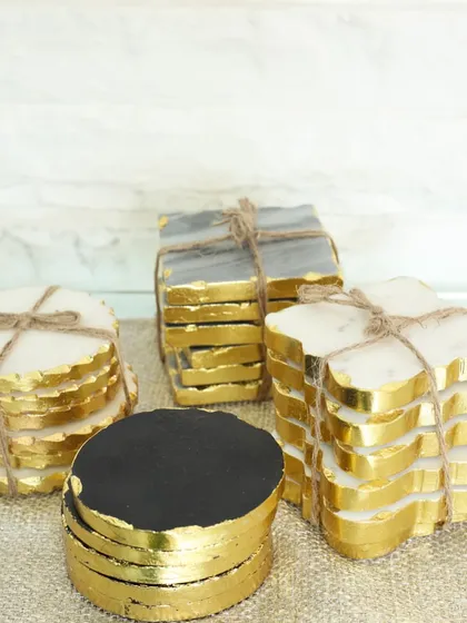 A display of our handcrafted marble coasters in various shapes, from classic rounds to playful flowers and squares. Each set is carved from natural stone, offering unique beauty for your home.