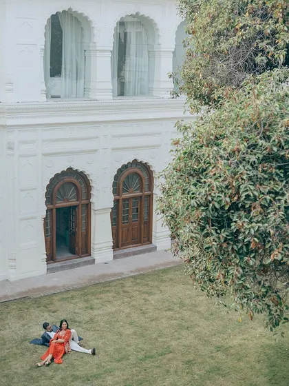 An aerial-style shot of a couple relaxing on the lawn of a palace courtyard.