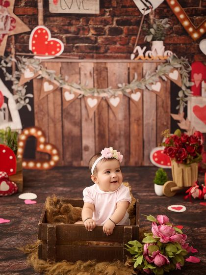 A sweet Valentine's themed portrait. The rustic wooden crate and heart decorations create a cozy and loving scene for this baby girl.