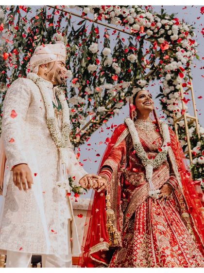 The joy of the Varmala ceremony. Dhwani and Aarshadd laugh as they exchange garlands under a shower of petals.
