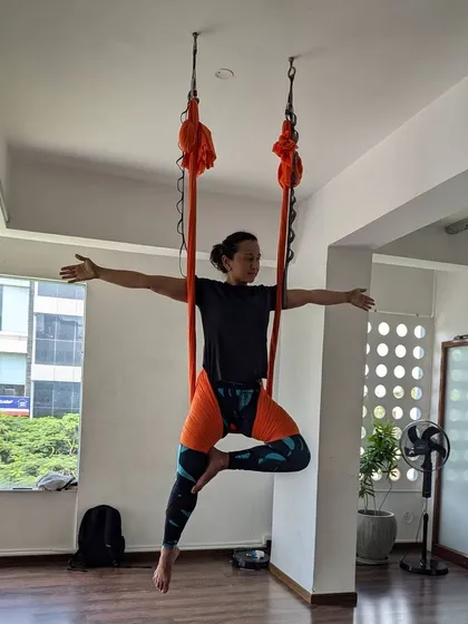 A student gracefully holds a pose, demonstrating the balance and core strength developed through consistent aerial yoga practice.
